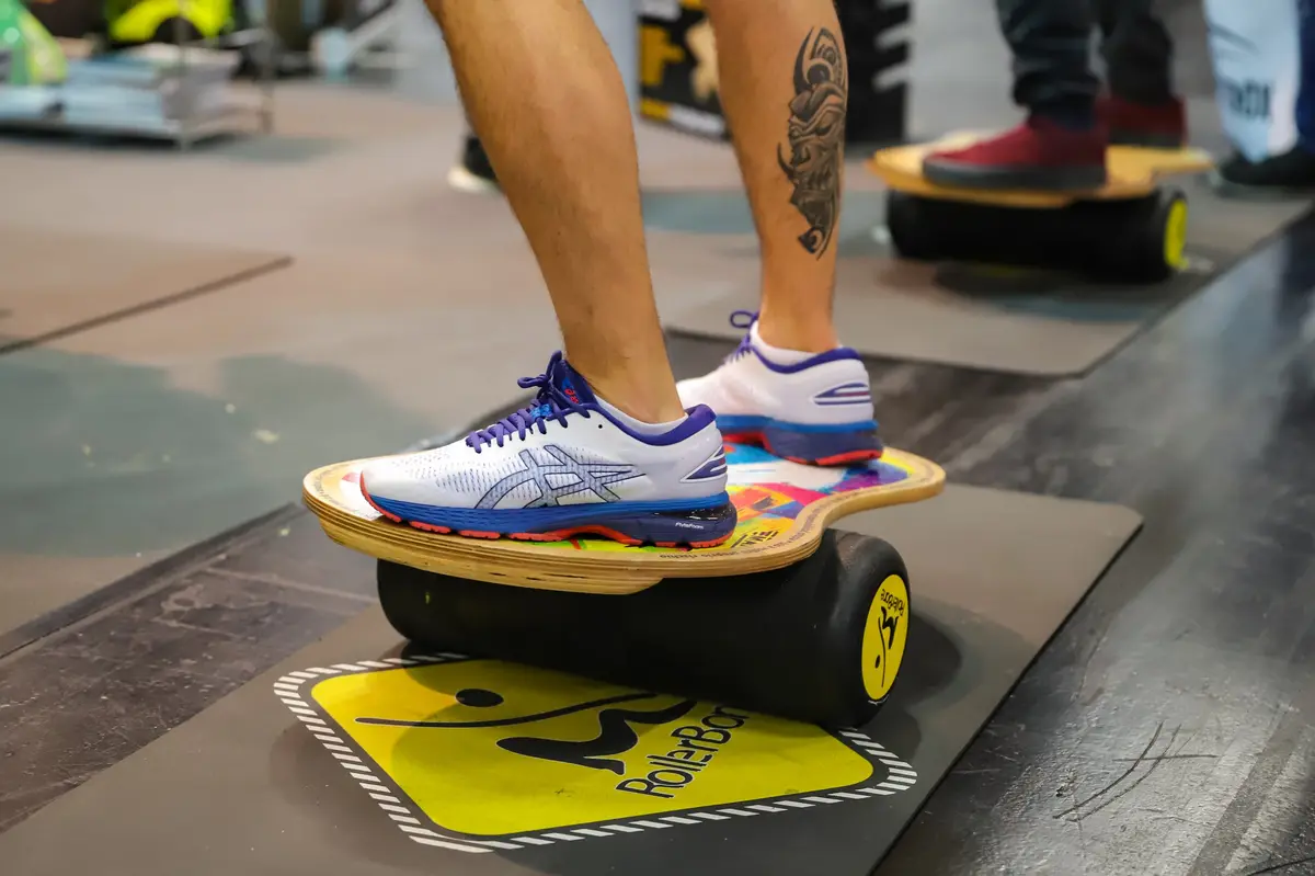 Füße auf einem Balance-Board mit Rolle auf dem Hallenboden