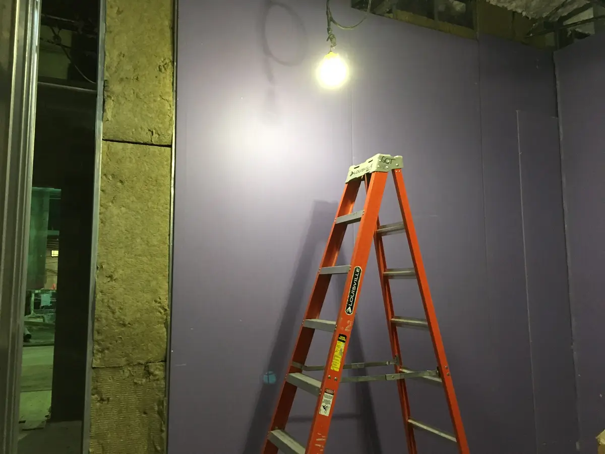 Frisch gespachtelte Trockenbauwand mit Leiter und Baulampe